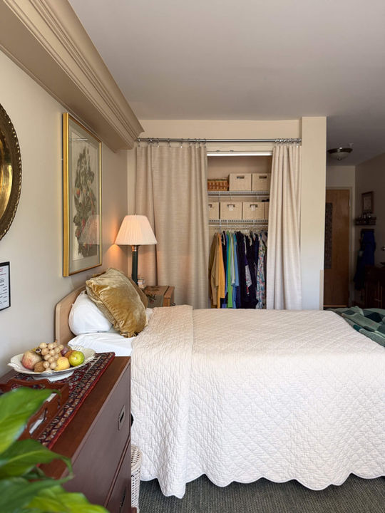 side view of bed with cream scallop quilt and semi-closed closet behind