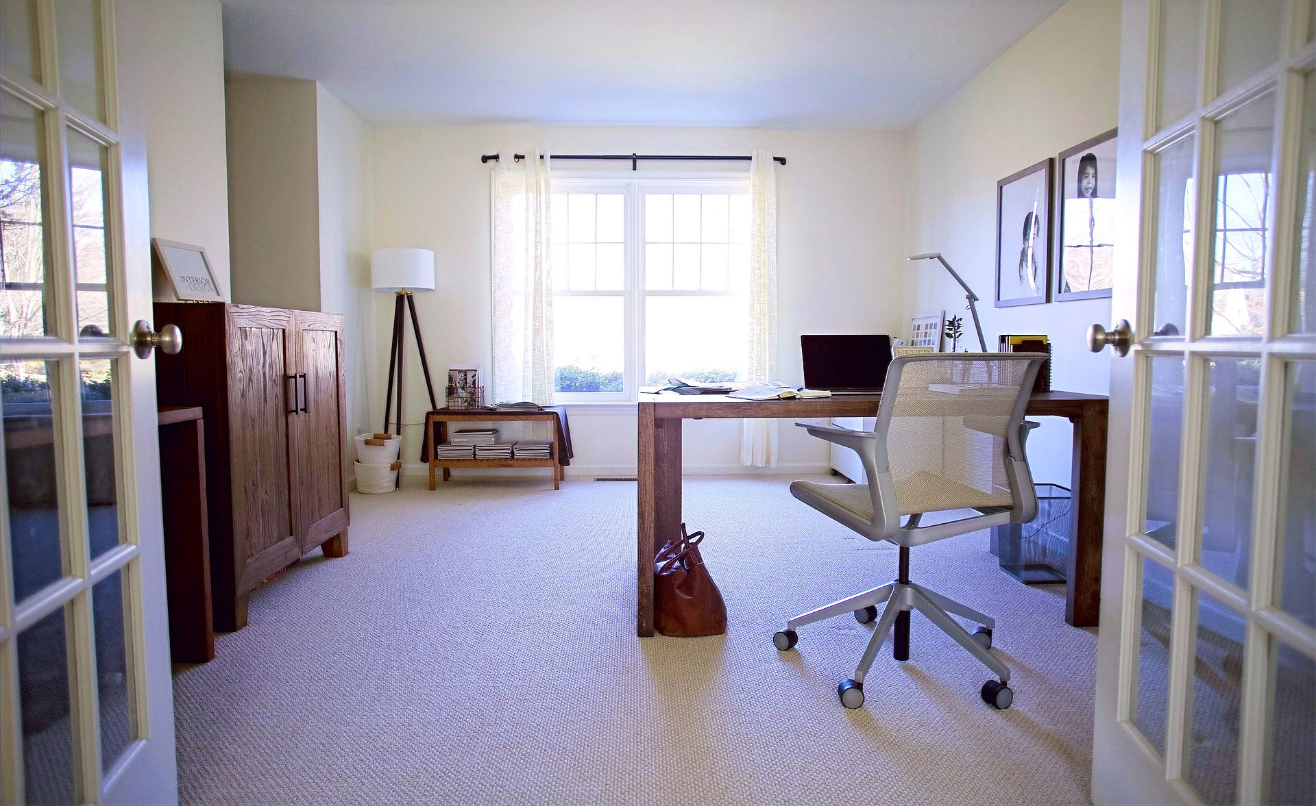 living room turned home office with timeless wood furniture, modern floor lamp, and abundant natural light