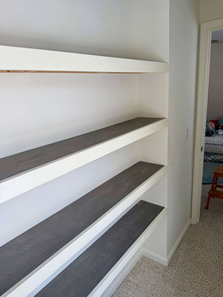 gray stained wood shelves with cream fascia installed in walk-in closet