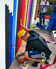 making of an artwork on a wall that is made out of adhesive cloth tapes in different colors