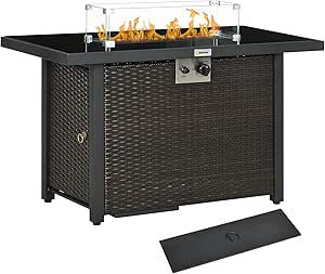 Black wicker outdoor fire pit table with flames behind a glass wind guard and a detached cover on a white background.