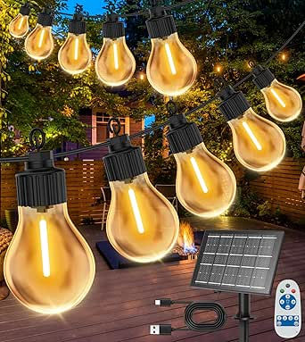 String lights glowing warmly at night in a backyard with trees and a wooden deck. Includes a solar panel and remote control. Cozy ambiance.