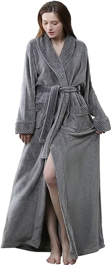 Woman in a gray bathrobe stands barefoot on a white background, holding the robe open to reveal her leg.