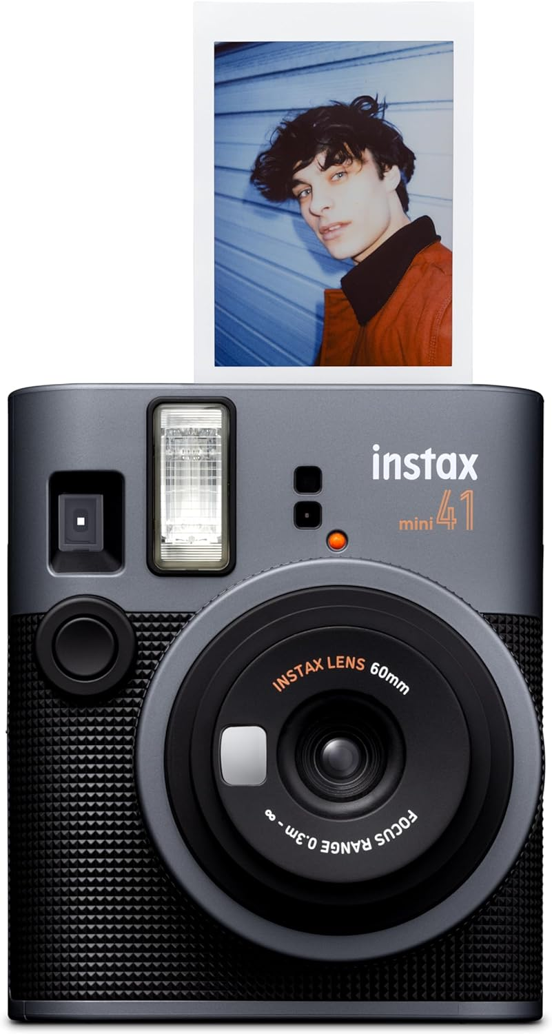 Instax mini 41 instant camera prints a portrait of a young man in an orange jacket against a blue wall.