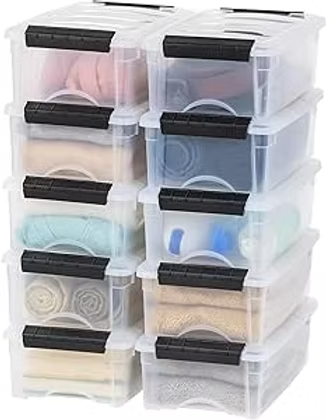 Stacked clear plastic storage bins with black latches, neatly holding folded clothes in pastel and neutral colors.