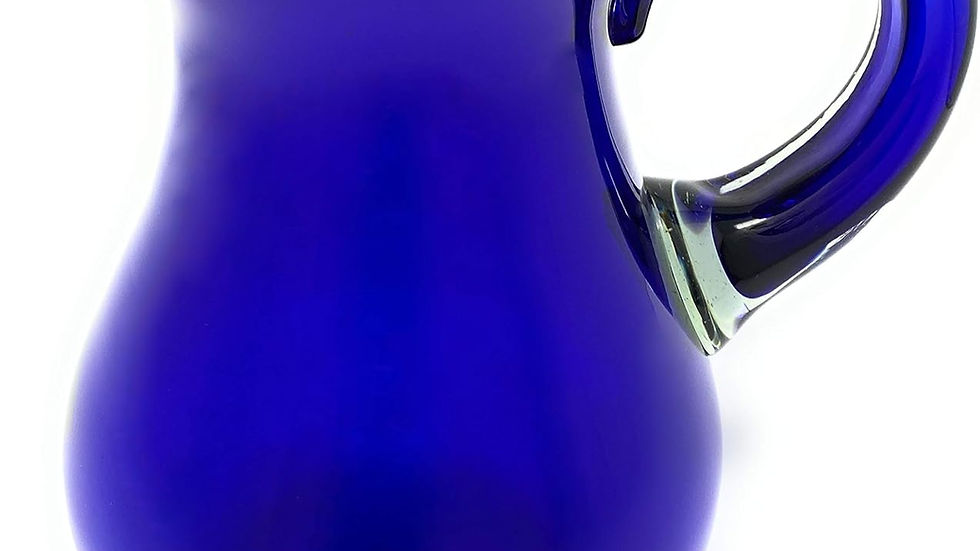 Blue glass pitcher with a wide spout and handle on a white background. The vibrant cobalt color stands out.