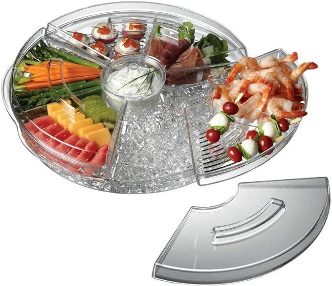 Clear platter filled with assorted snacks including shrimp, veggies, and fruits. Central dip container. Lid placed nearby.