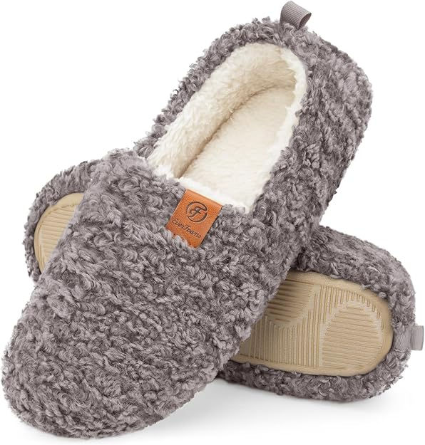 Cozy gray slippers with curly texture, cream interior, and beige soles. Features a brown tag with "EverFoams" logo. Warm and inviting mood.
