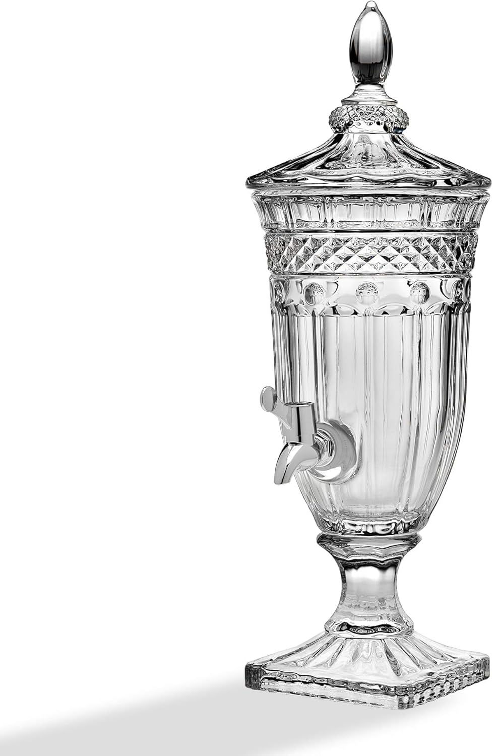 Ornate clear glass beverage dispenser with spigot and lid on a white background, elegant and decorative.
