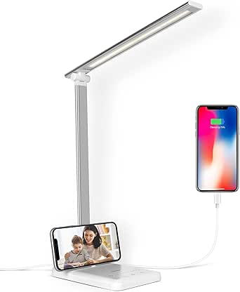 White desk lamp with two smartphones charging: one on the base showing a woman and child, one upright on the right.