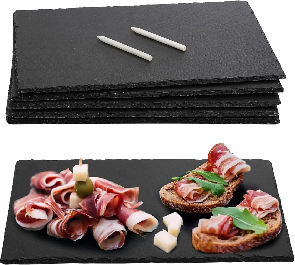 Stacked black slate serving boards with two white chalk sticks; bacon roll appetizers on toast with greens and cheese.
