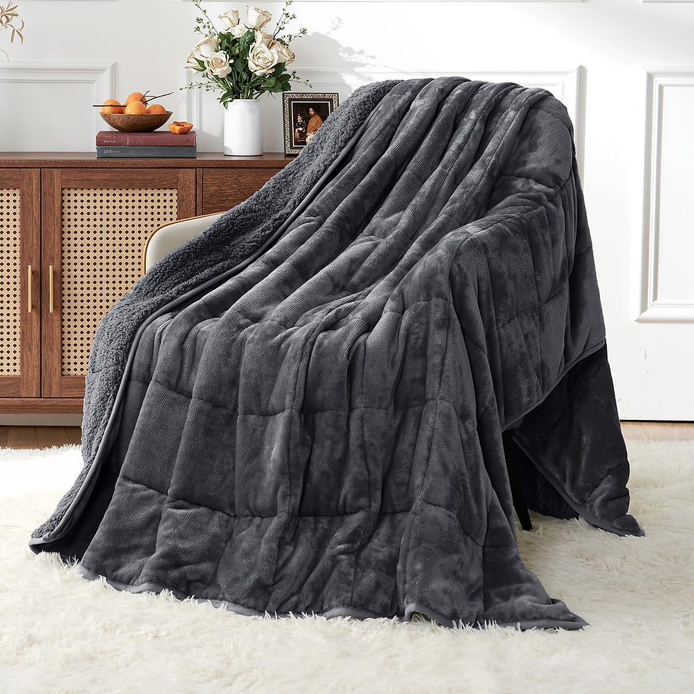 Dark gray plush blanket draped over a chair in a bright living room, beside a wood sideboard with flowers and fruit.