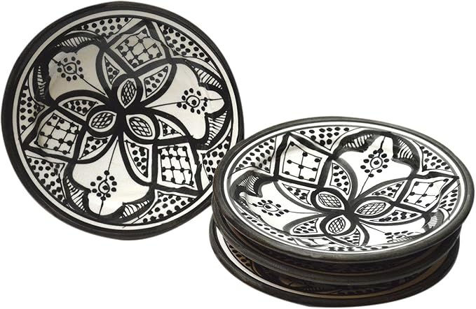 Black and white decorative plates with intricate floral designs are stacked against a white background, creating a stylish, artistic look.