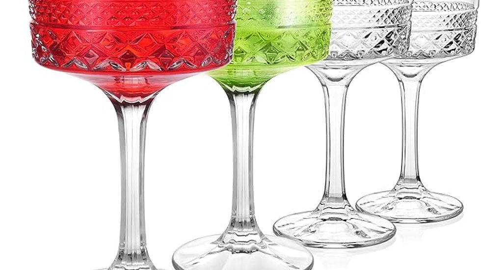 Four ornate cocktail glasses, two filled with red and green drinks garnished with a cherry and mint, stand in a row on a white background.