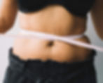 A photo of a young woman measuring her waist.
