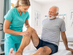 A nurse looking at an older man's legs, portraying chronic disease.