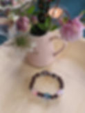 Completed Life Beading bracelet in front of a pink jug of flowers
