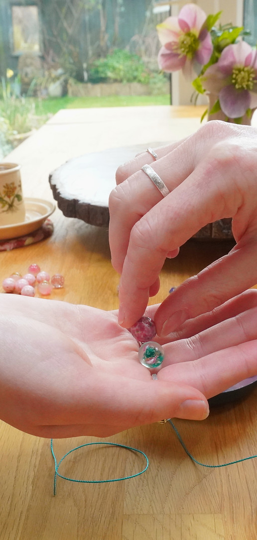 Close up of one person takng a pink bead from another person's open palm.