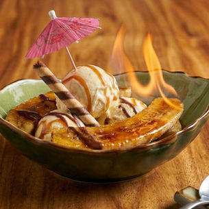 A dramatic photo of the Flambé Banana dessert catching fire in our signature green boat-shaped bowl.
