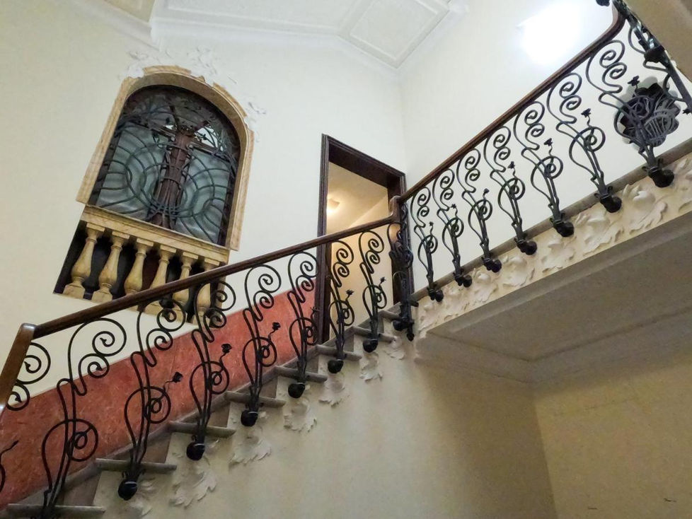 a staircase with a wrought iron railing and a stained glass window