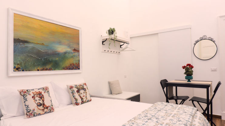 a bedroom with a painting on the wall above the bed