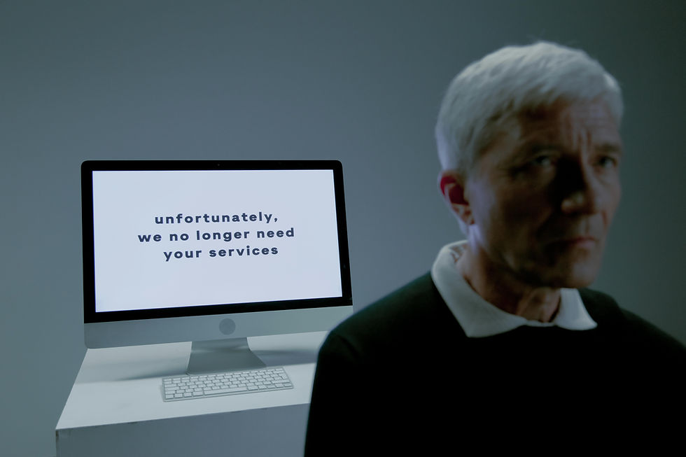 older professional man reading job termination message on computer screen representing AI-driven tech layoffs and age discrimination