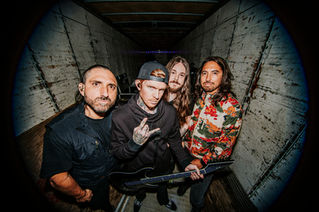 Four-piece rock band posing for a fisheye group portrait inside the back of a cargo truck, photographed by Maxwell Thomason