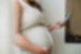 Pregnant woman holding belly and phone