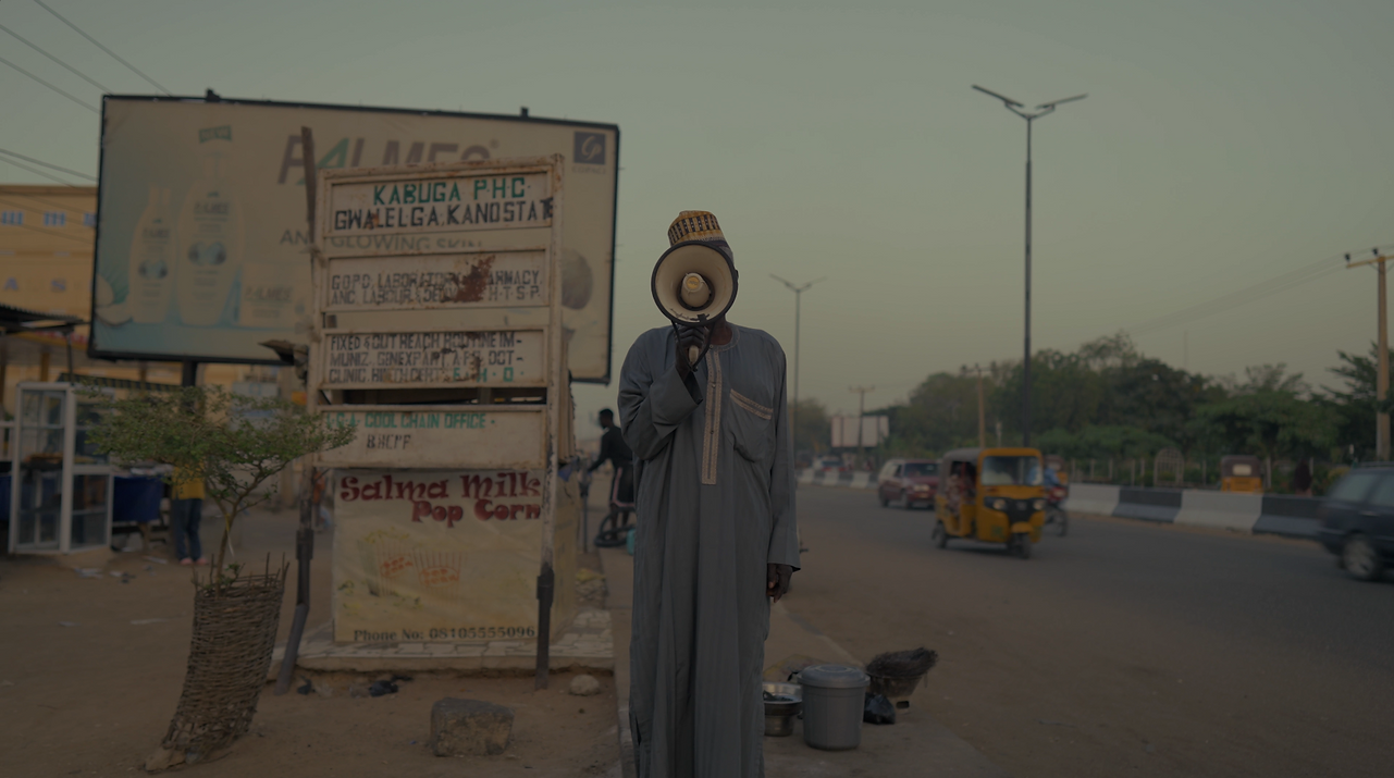 Color-graded scene of a person standing next to large crates in a hazy, industrial setting.