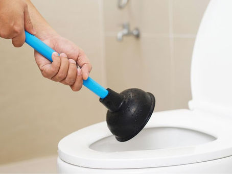 A Man Holding a Plunger As He Tries to Unblock His Toilet. Three Reasons You Should Never Leave a Blocked Drain