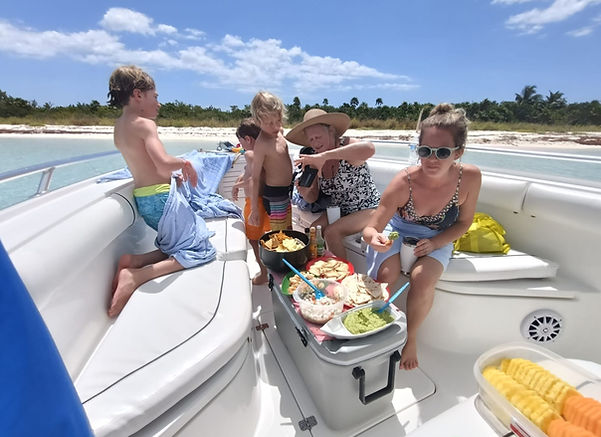 Family enjoying freshly prepared food aboard a private boat charter in Cozumel