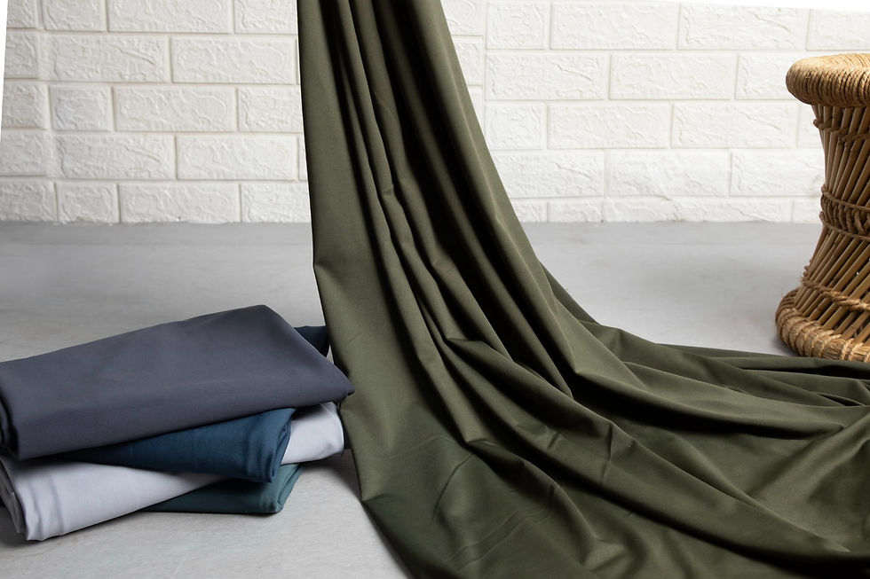 Green drape and folded fabrics; brick wall in background; Fabric Manufacturer