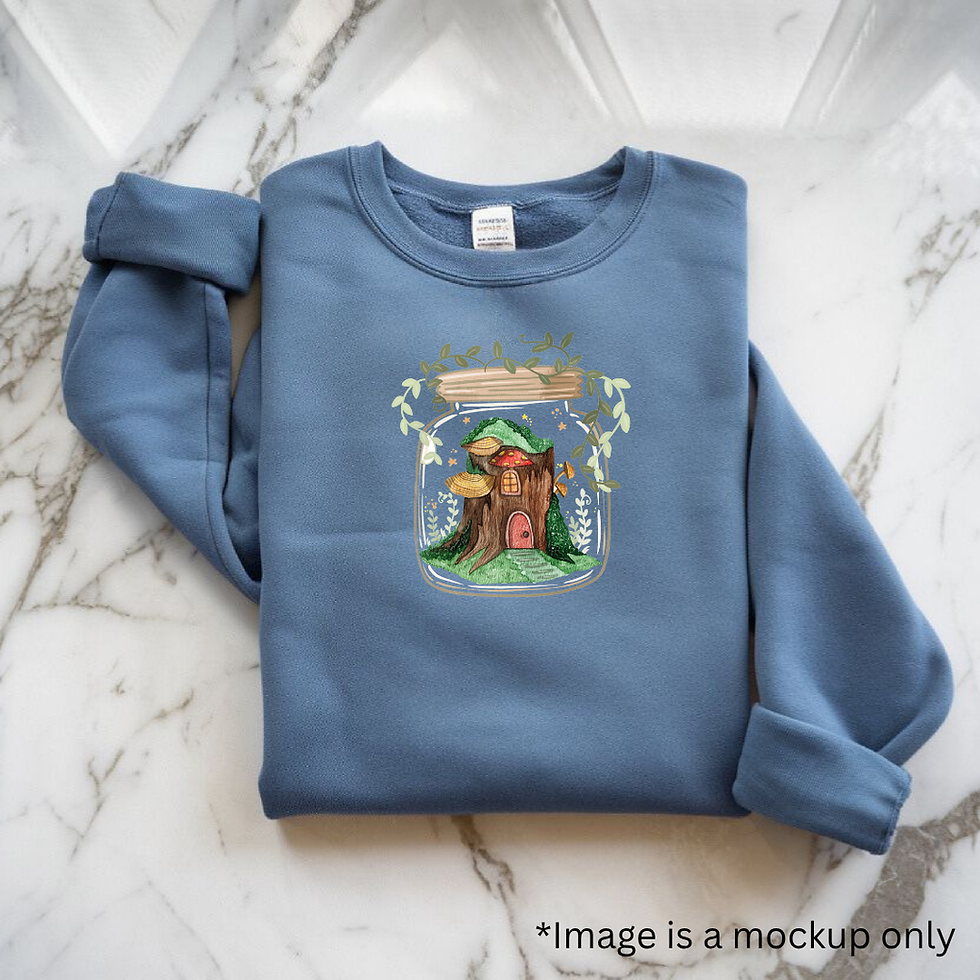 A mockup of an iron on transfer (a small tree house in a jar with decorative leaves) on a blue jumper