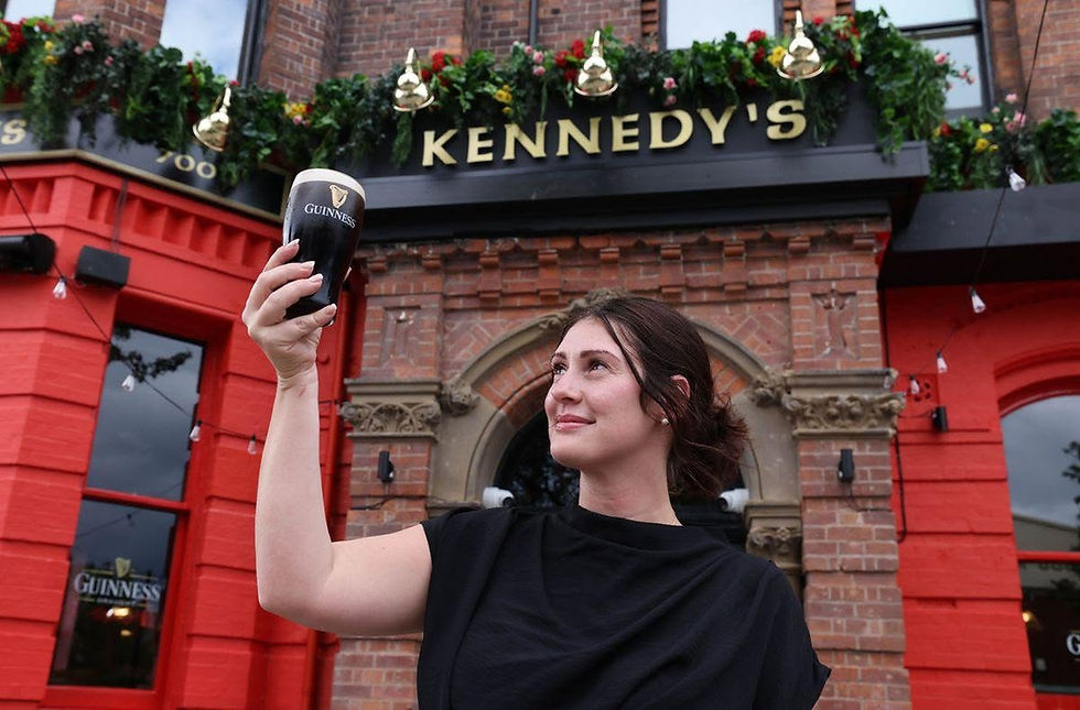 Our manager, Natalie, stood in front of the front entrance, holding a perfect pint of Guinness with a slight tilt to show the pour quality.