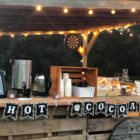 Hot cocoa bar all set up with a sign, hot cocoa, and condiments