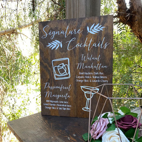 Customer wedding cocktails displayed on a wooden sign on the bartop