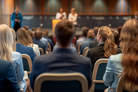 attendees facing a stage with speakers in a conference