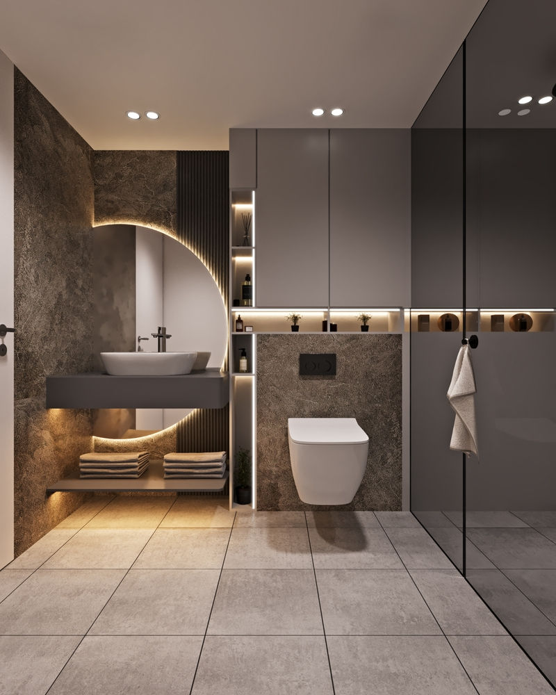 Modern luxury bathroom with floating sink, wall toilet, glass shower, warm backlighting, towels, and large mirror.