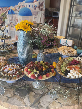 Elegant grazing table featuring charcuterie, fresh fruit, appetizers, and floral arrangements