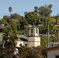 Small white church tower nestled among green trees