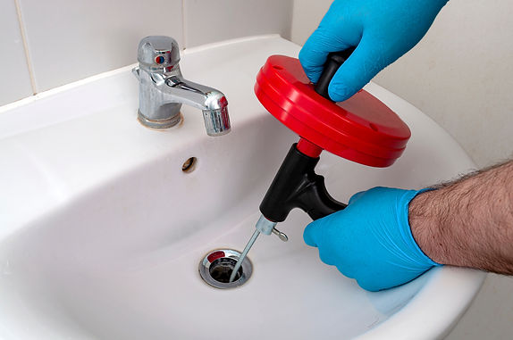 plumber using a drain snake to unclog a sink