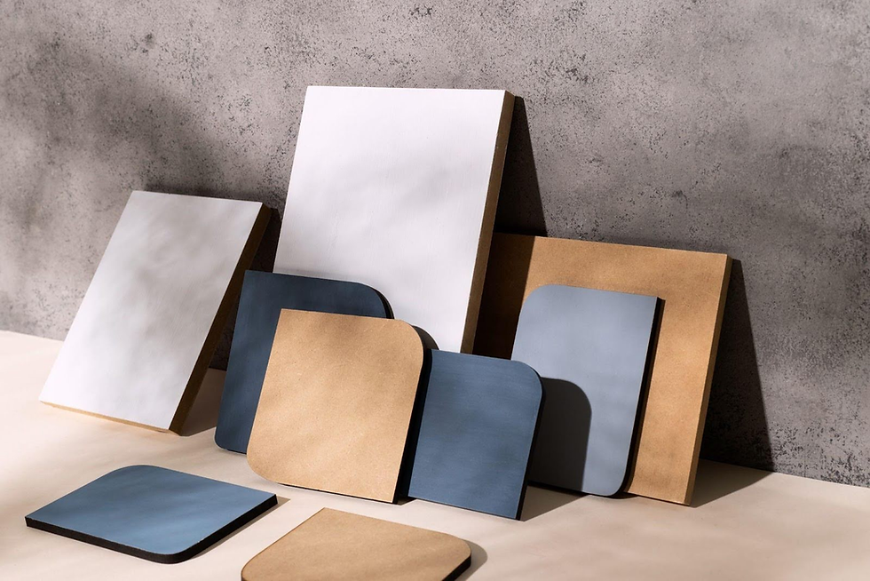 Assorted rectangular boards in white, brown, and blue with rounded corners, set against a textured gray wall in soft lighting.
