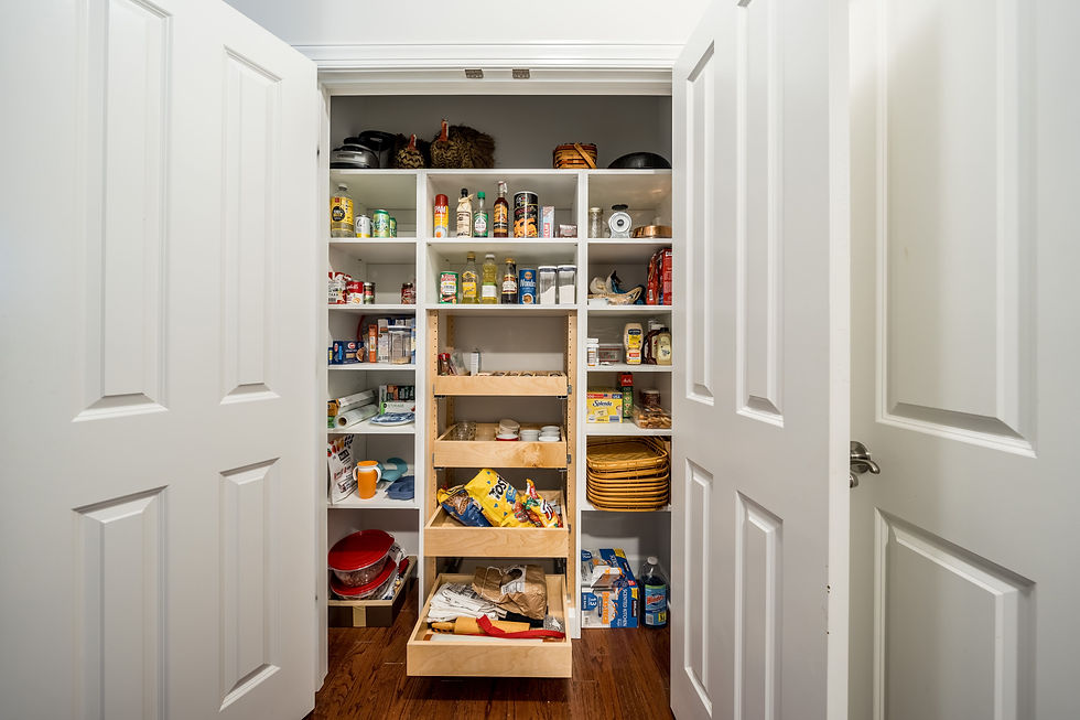 Open pantry with shelves full of food items, cans, and condiments. Wooden drawers partially open. Bright, organized space.