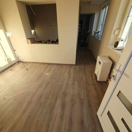 Rekonstrukce prázdného pokoje, dřevěná podlaha, světlé stěny, připraveno k dokončení.