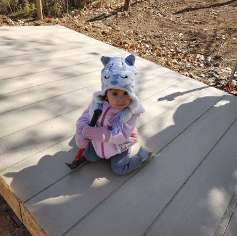Young girl holding a hammer wearing a fox beanie and pink coat