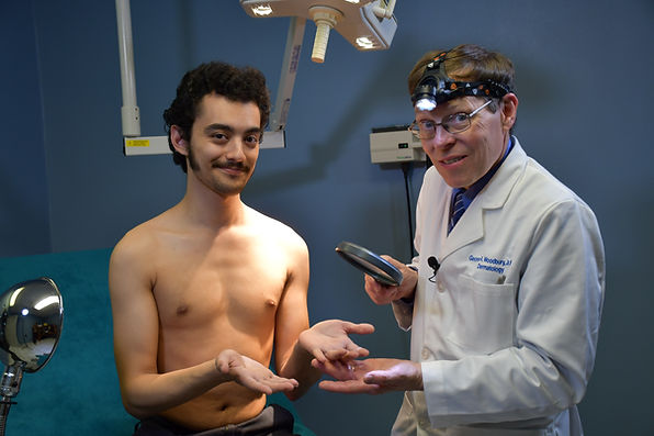 Cordova Dermatologist Dr. George Woodbury does a Melanoma screening on a young man in his Memphis Dermatology office