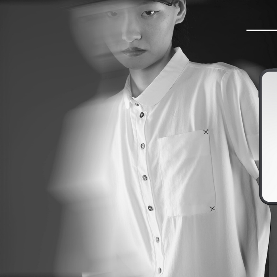 Women’s short-sleeve black and white button-up shirt with asymmetrical sheer panel design.