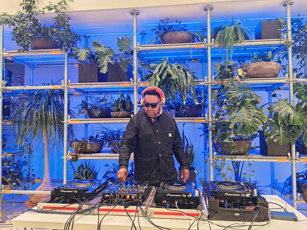 Mo Laudi mixing a DJ set in front of plants and blue lighting