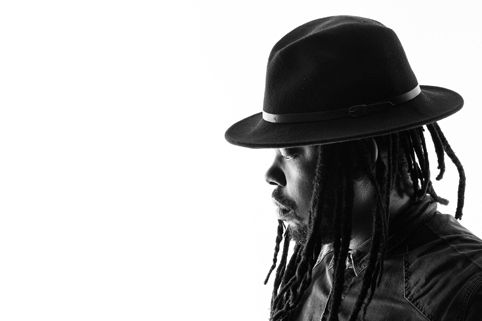 Black-and-white profile portrait of Mo Laudi wearing a hat