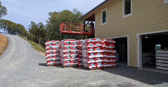 Stacks of Rockwool in front of a scissor lift, next to a home with Hardiplank siding